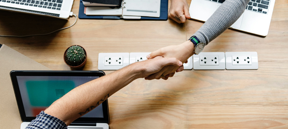 Sich schttelnde Hnde ber einem Schreibtisch mit Laptops, Foto: rawpixel/unsplash