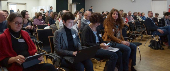 Personen sitzen in einem Konferenzsaal  DVV/ Thomas Umhey